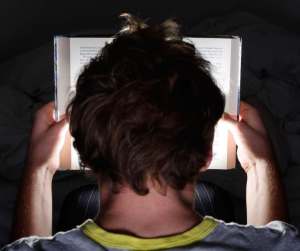Ragazzo legge al buio un romanzo